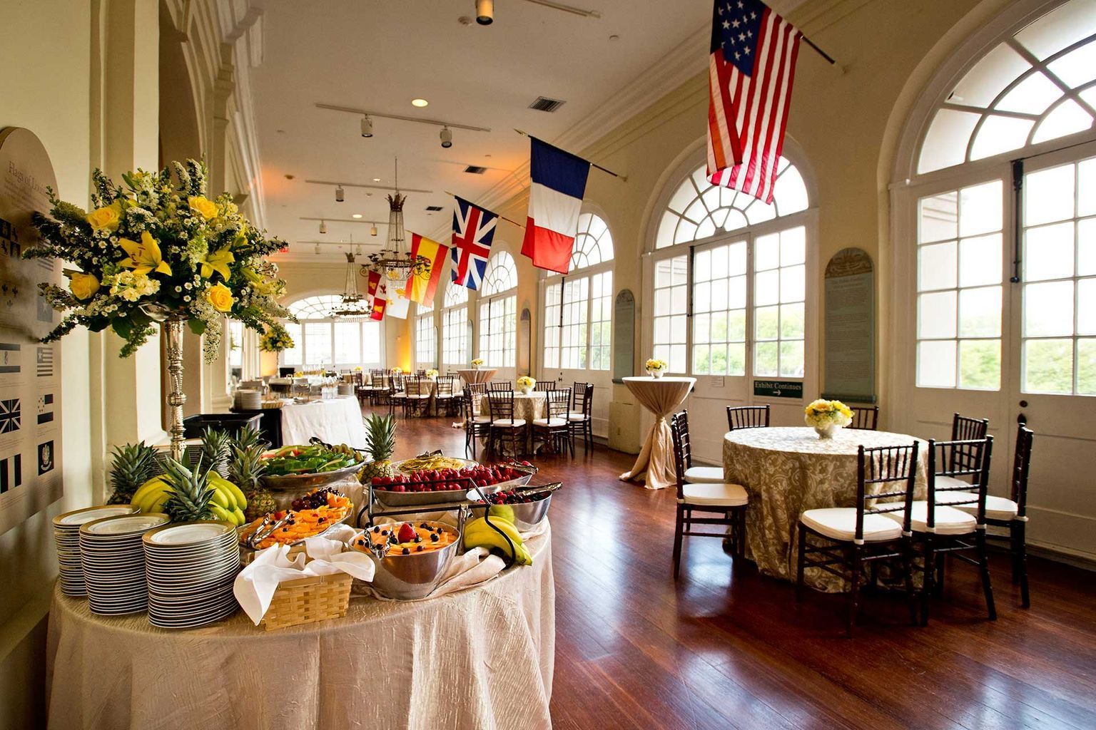 A large room with tables and chairs and flags hanging from the ceiling