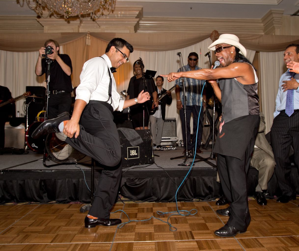 A group of men are dancing on a stage in front of a band