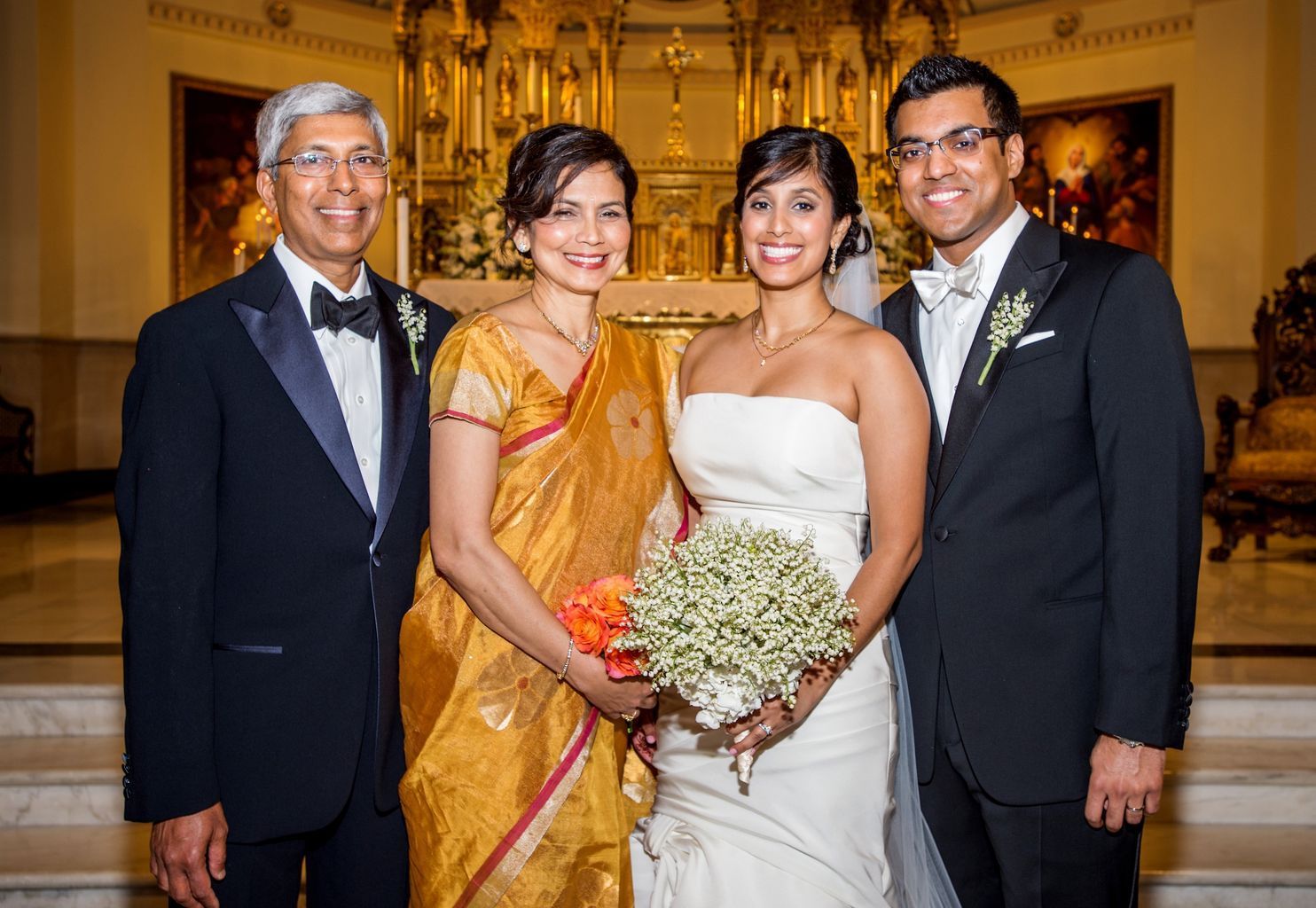 A bride and groom are posing for a picture with their parents.