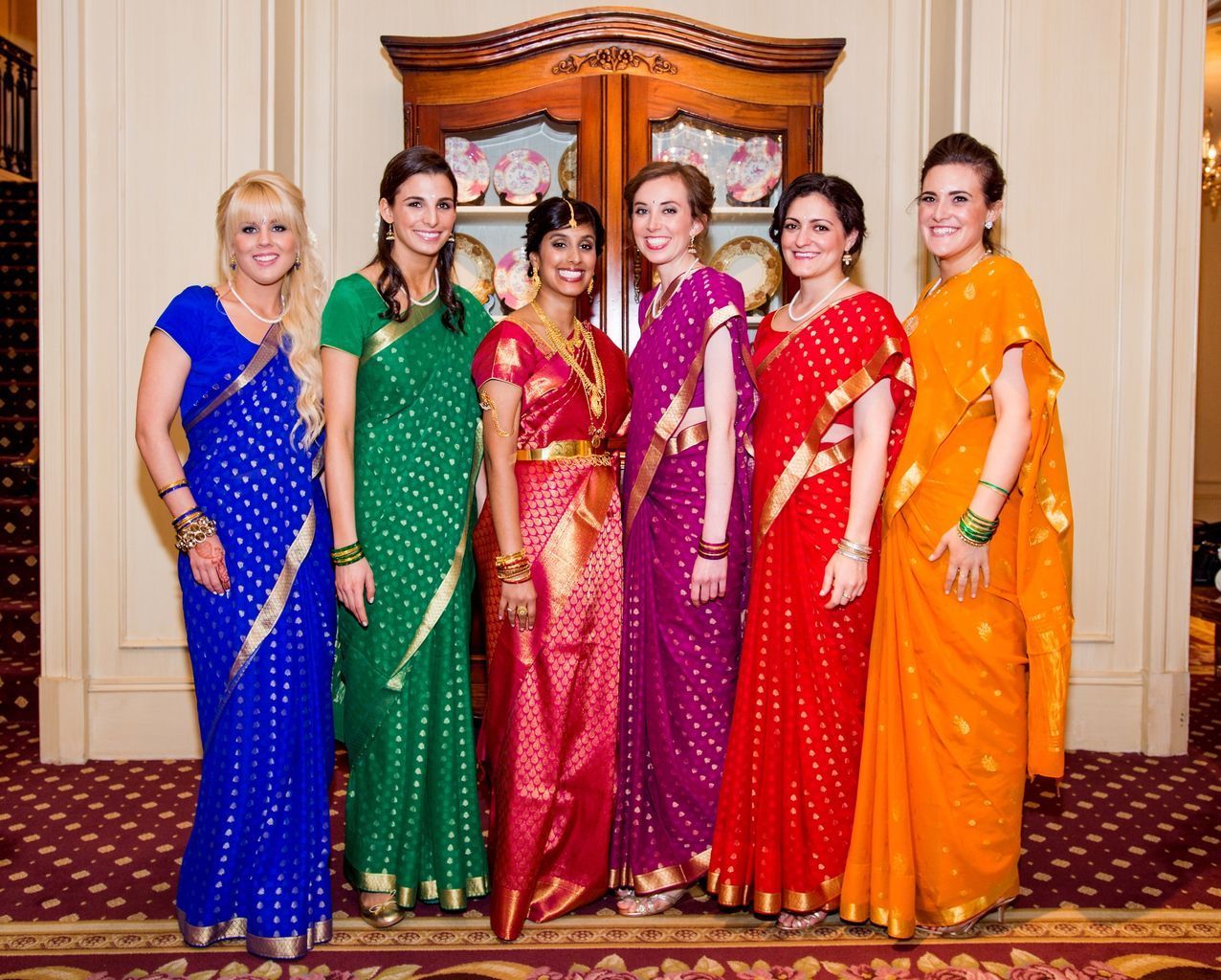 A group of women are posing for a picture in their saris