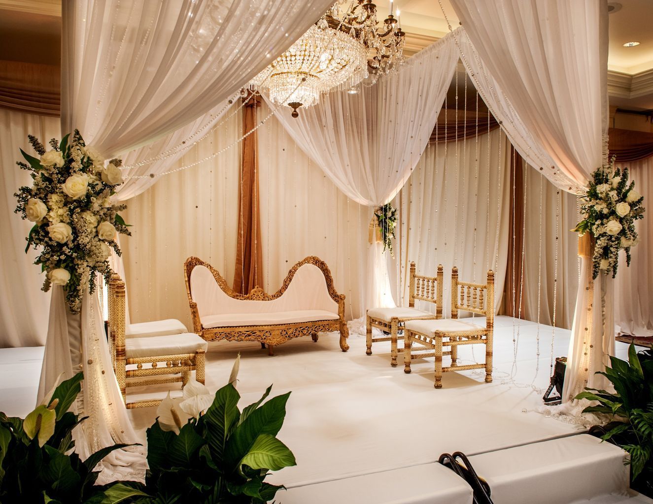 A wedding stage with a couch and chairs under a canopy