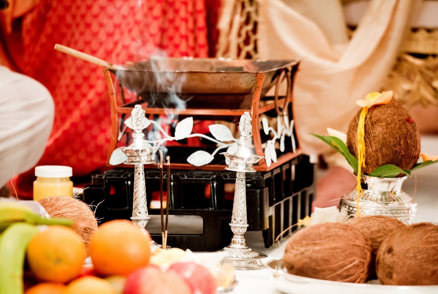 A person is cooking food on a stove in front of a table with fruit and candles.