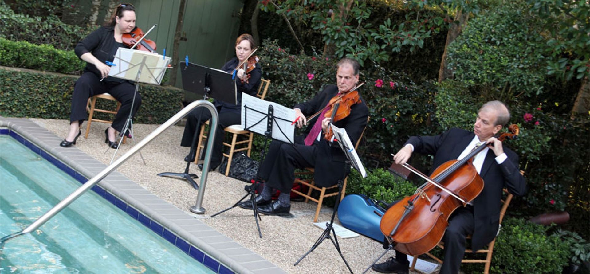 A group of people are playing violins and cello by a pool.