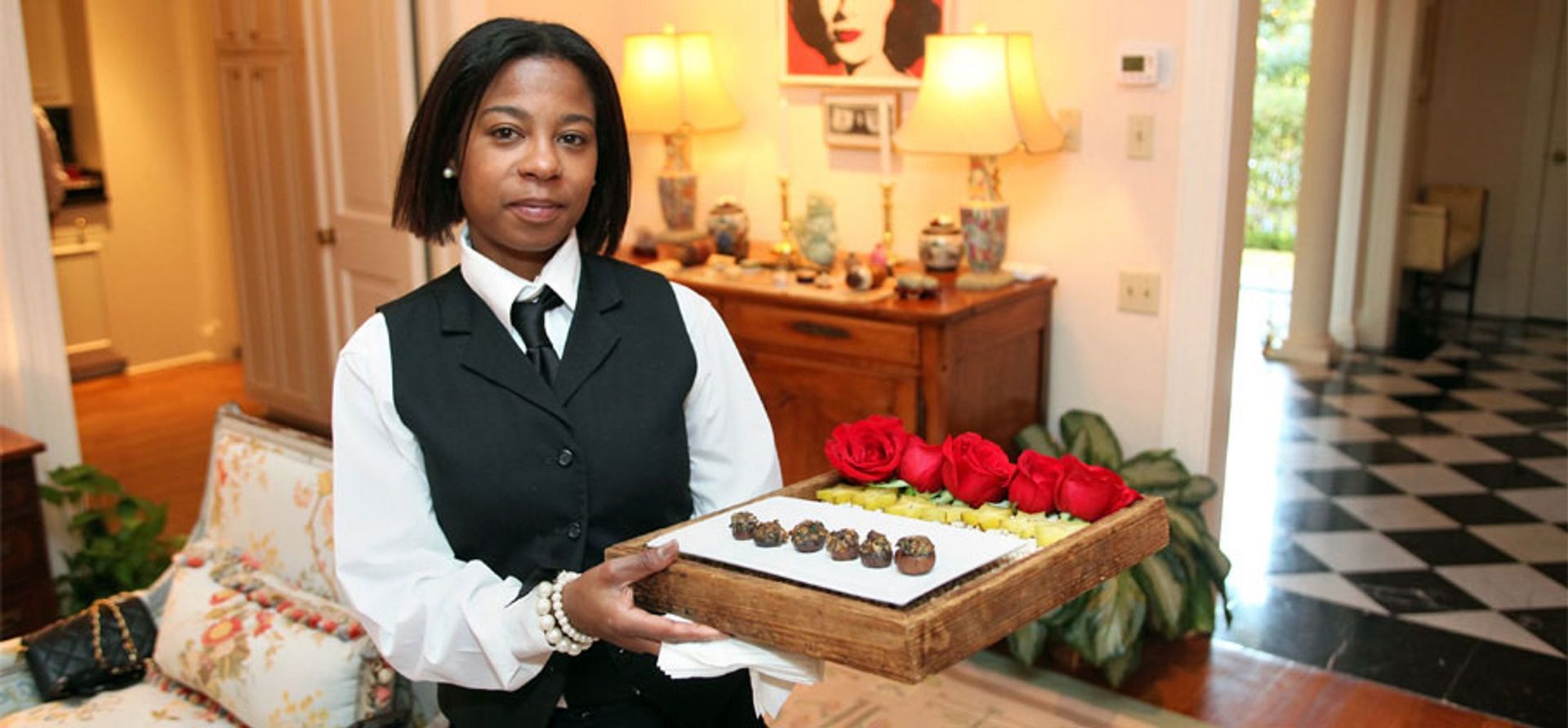 A woman is holding a tray of food in a living room.