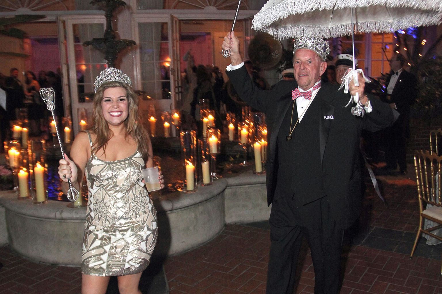 A man and a woman are holding umbrellas in front of a fountain.