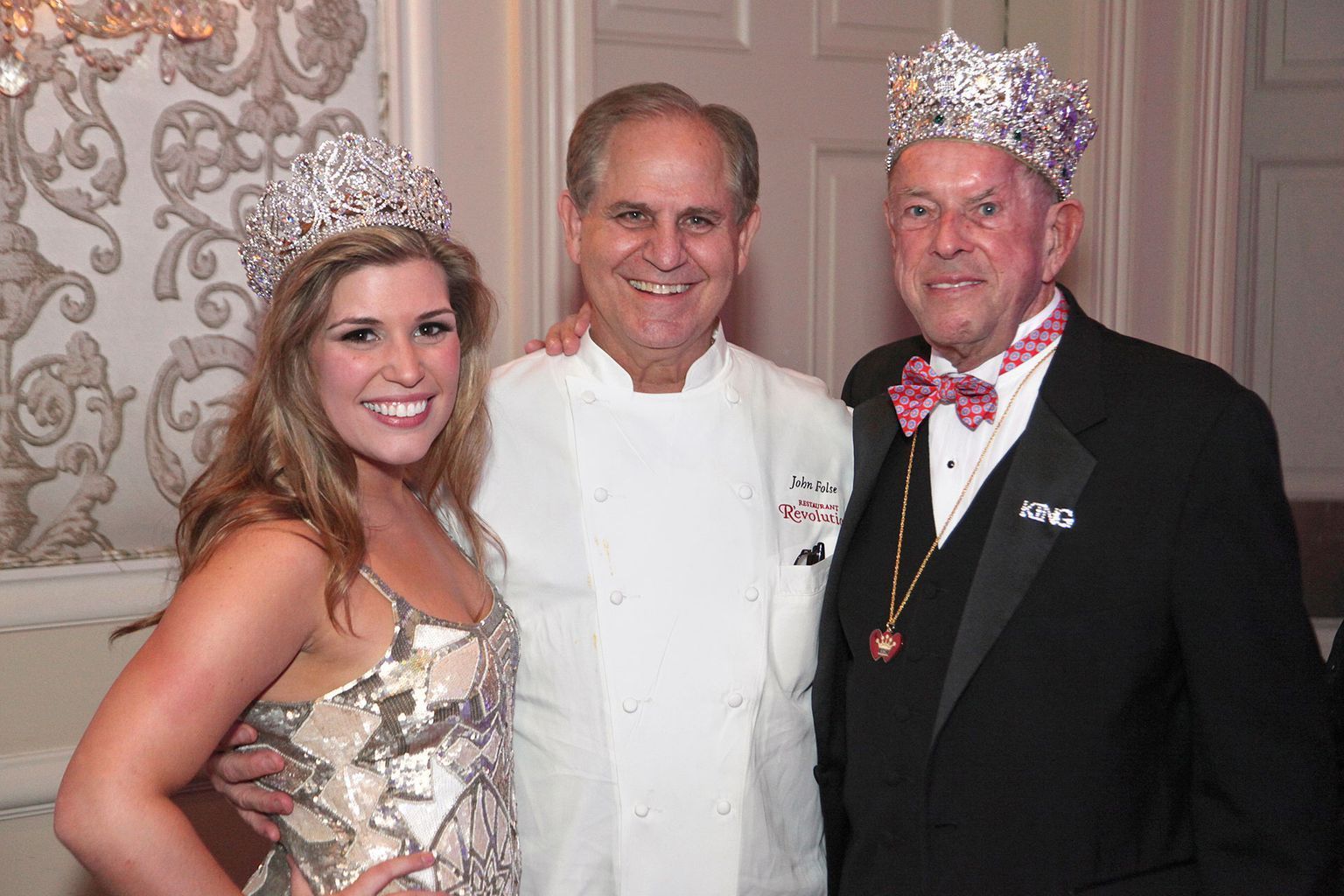 A woman in a dress is posing for a picture with two men wearing crowns.