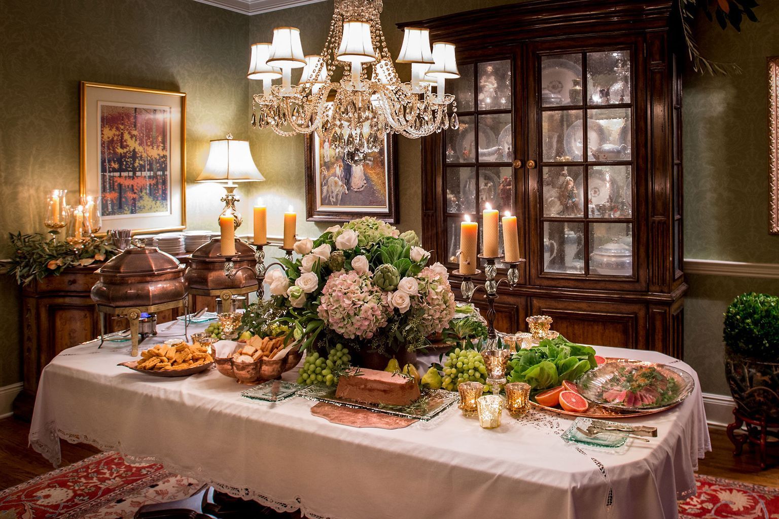 A dining room table with a white tablecloth and a chandelier.