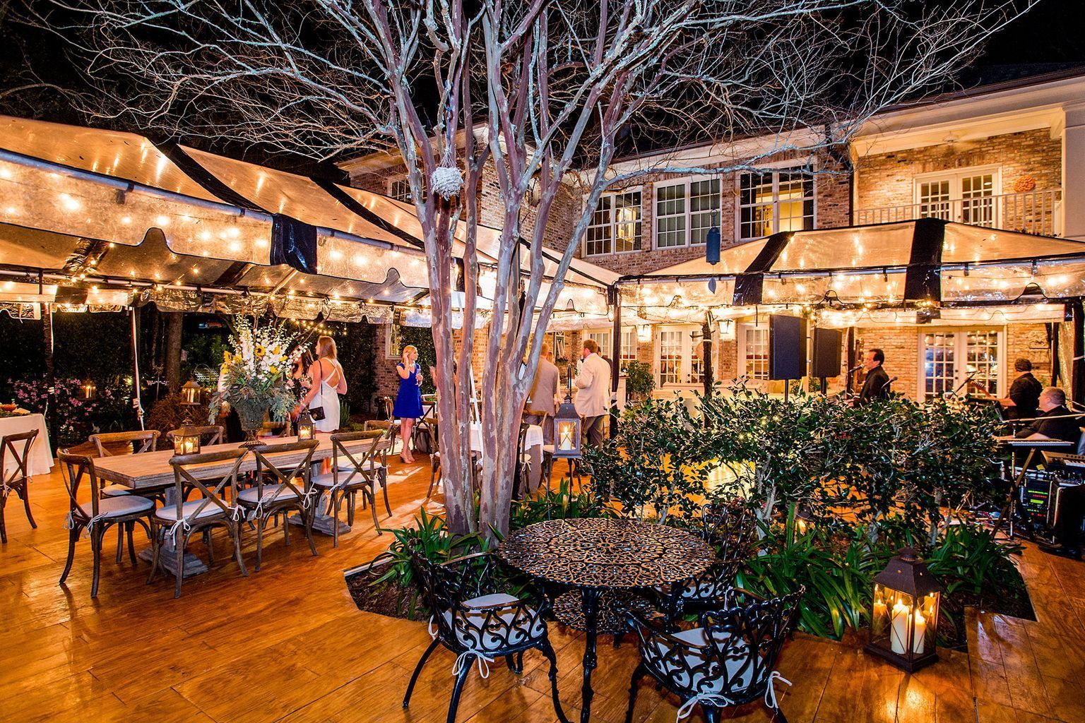 A restaurant with tables and chairs under a tree at night.