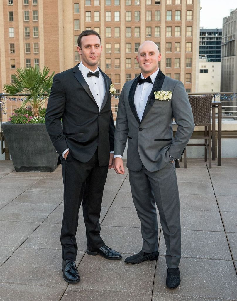 Two men in tuxedos standing next to each other on a rooftop