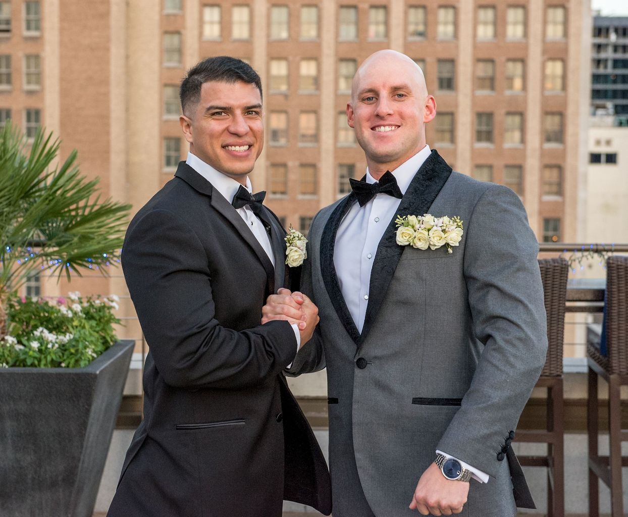 Two men in tuxedos are shaking hands in front of a building.