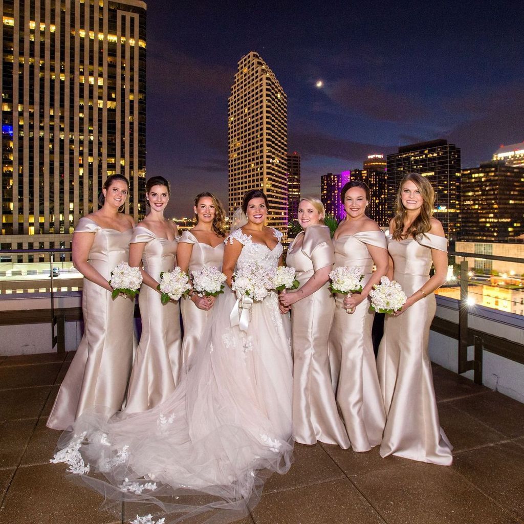 A bride and her bridesmaids pose for a picture on a balcony