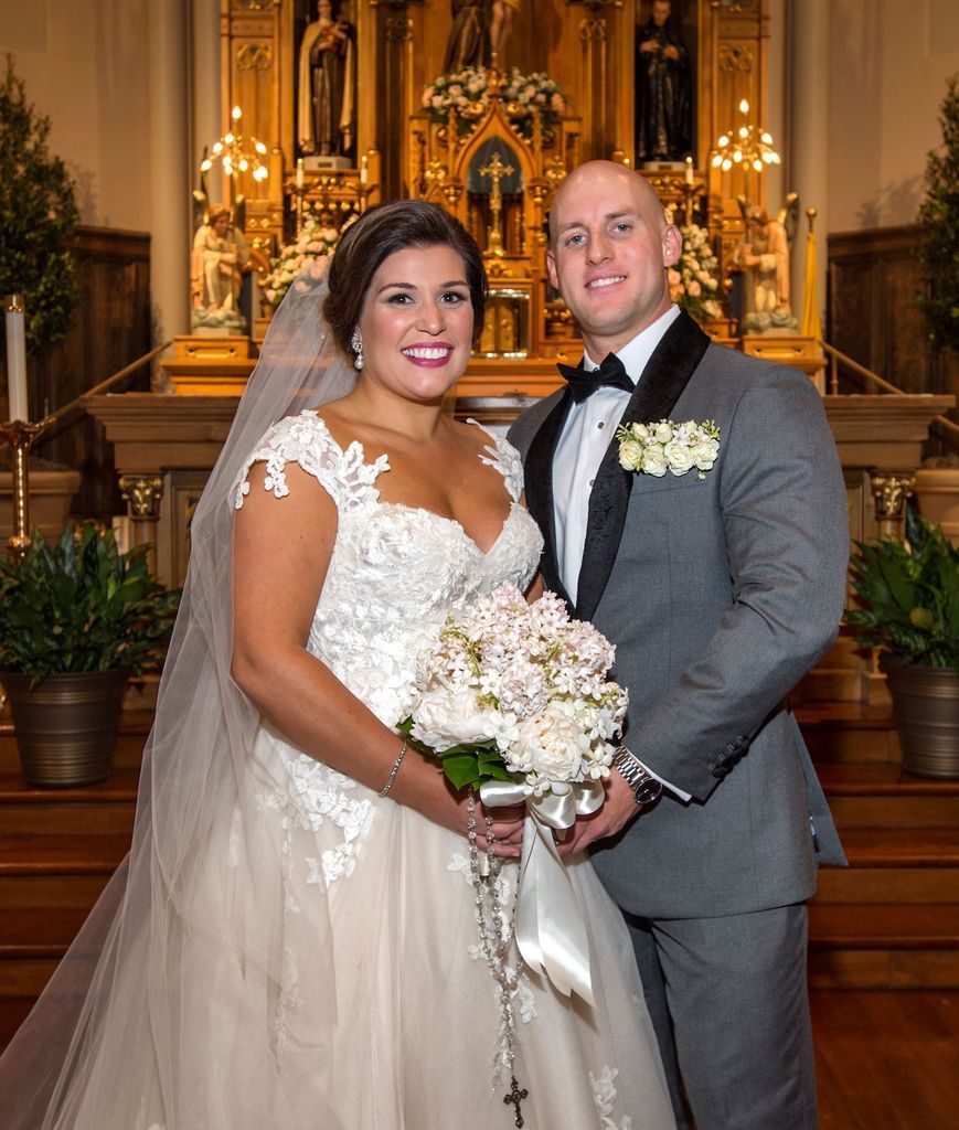 A bride and groom are posing for a picture in front of a church altar.