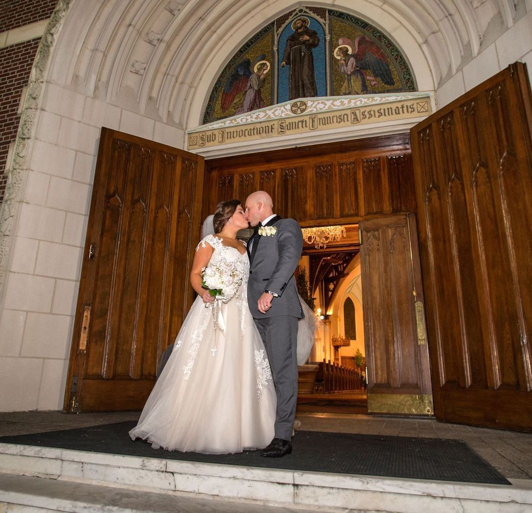 A bride and groom kissing in front of a church
