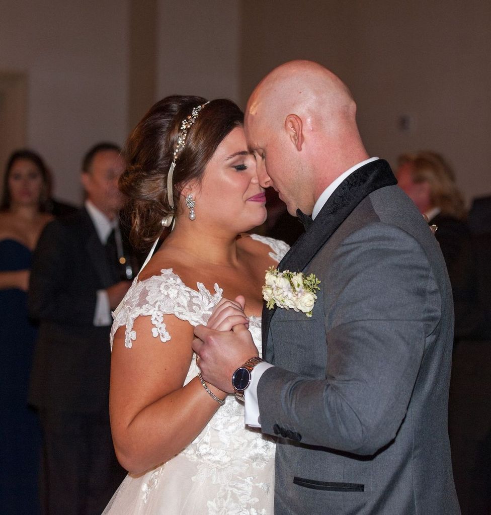 A bride and groom are dancing together at their wedding reception