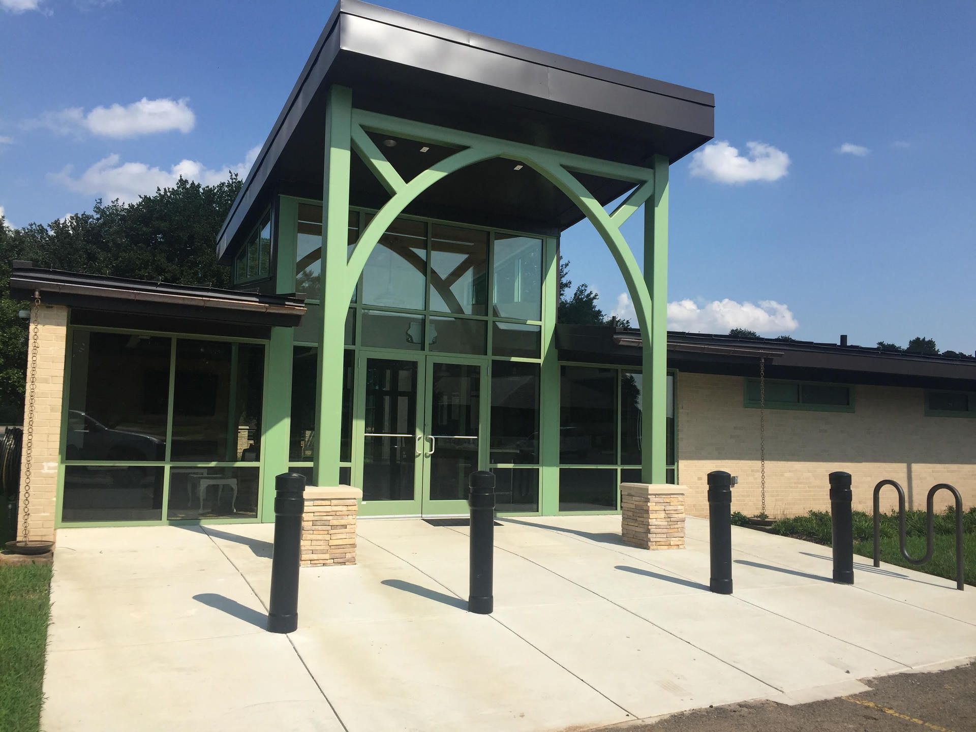 A building with a green entrance and a concrete walkway