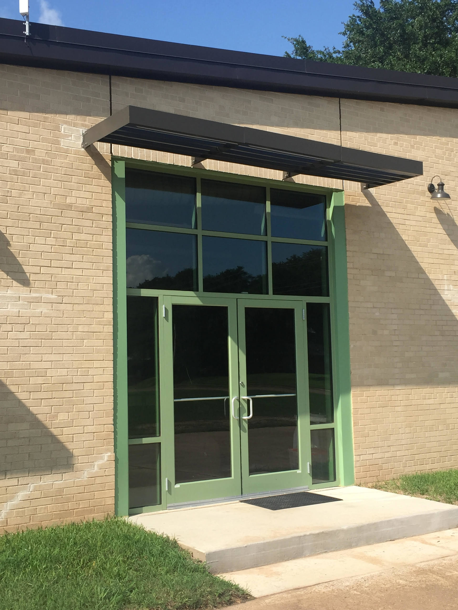 A brick building with green doors and a canopy