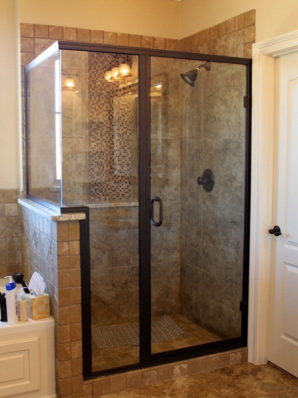 A bathroom with a walk in shower with a black frame