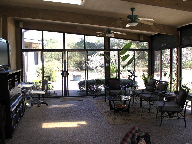 A living room with a lot of windows and a ceiling fan