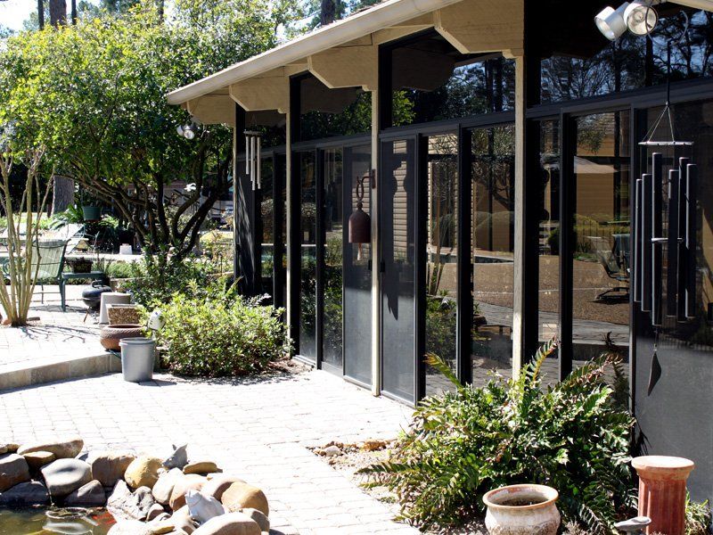 A house with a lot of windows and a pond in front of it