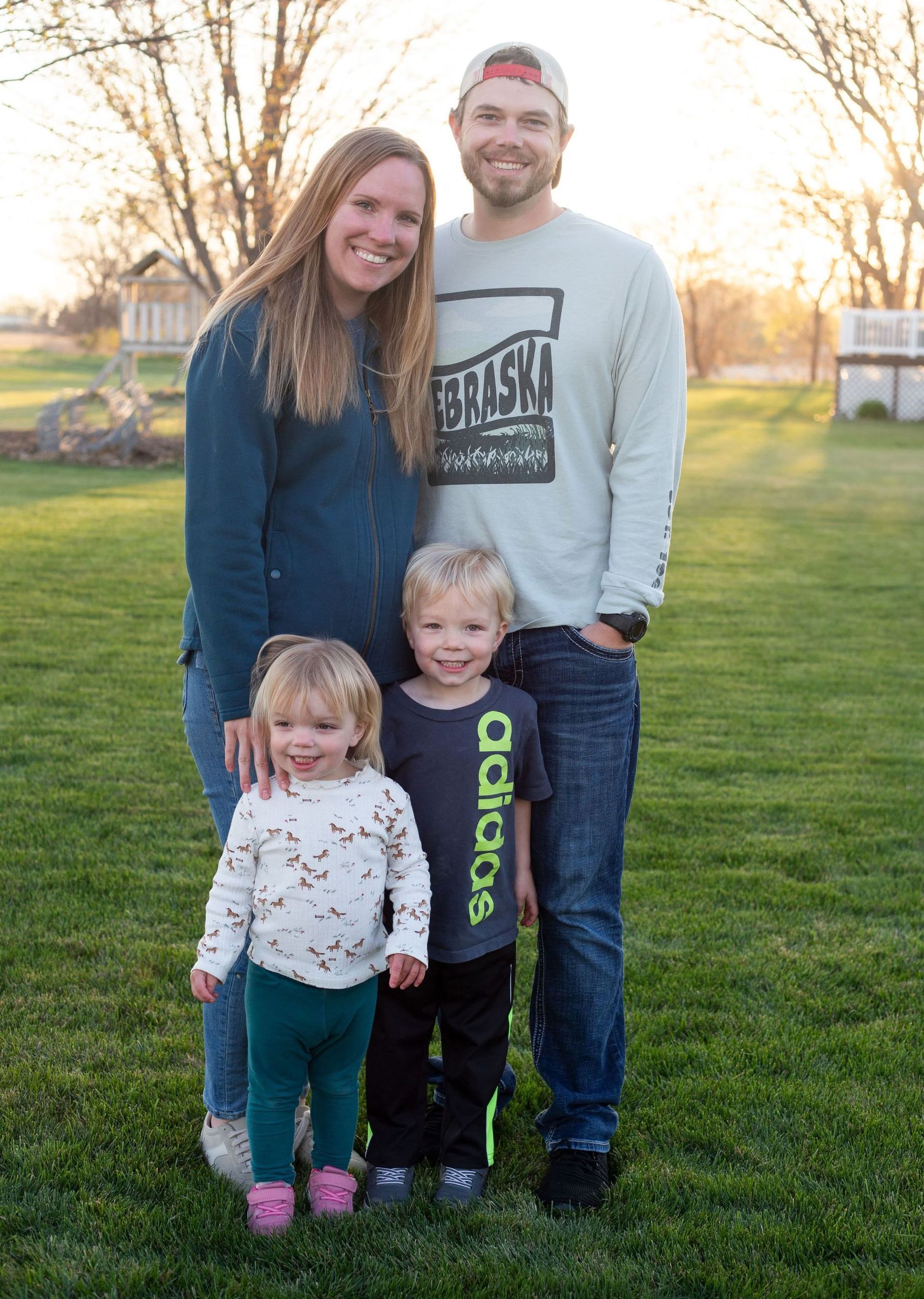 A man in a maroon shirt and blue jeans is standing with his hands in his pockets.
