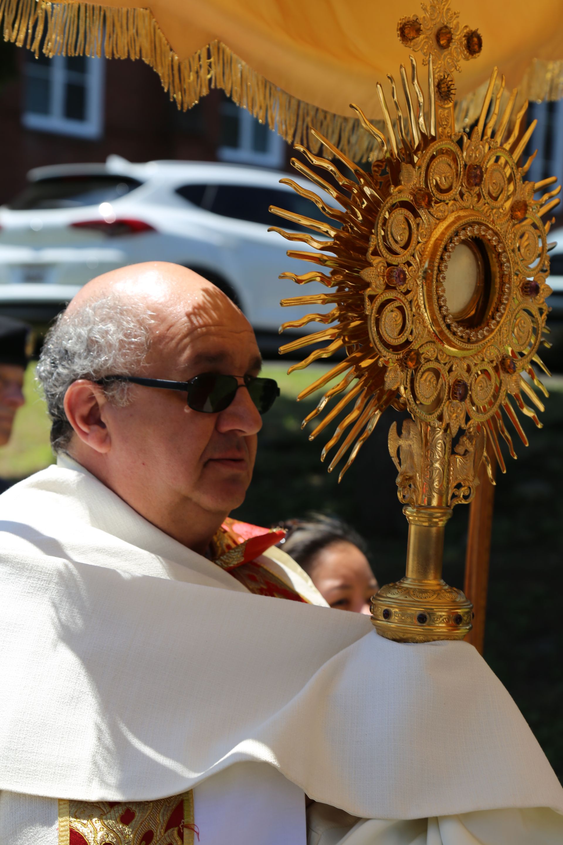 A man in a white robe is holding a golden object.