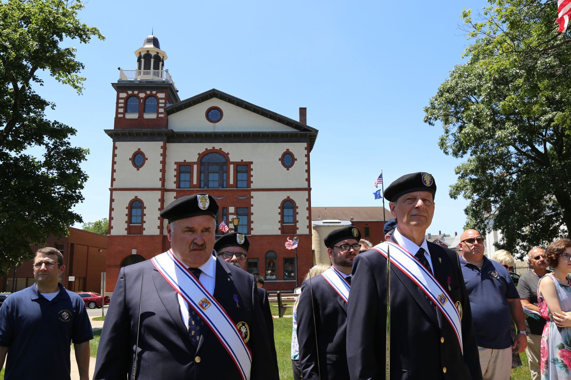 A group of men are marching in front of a large building