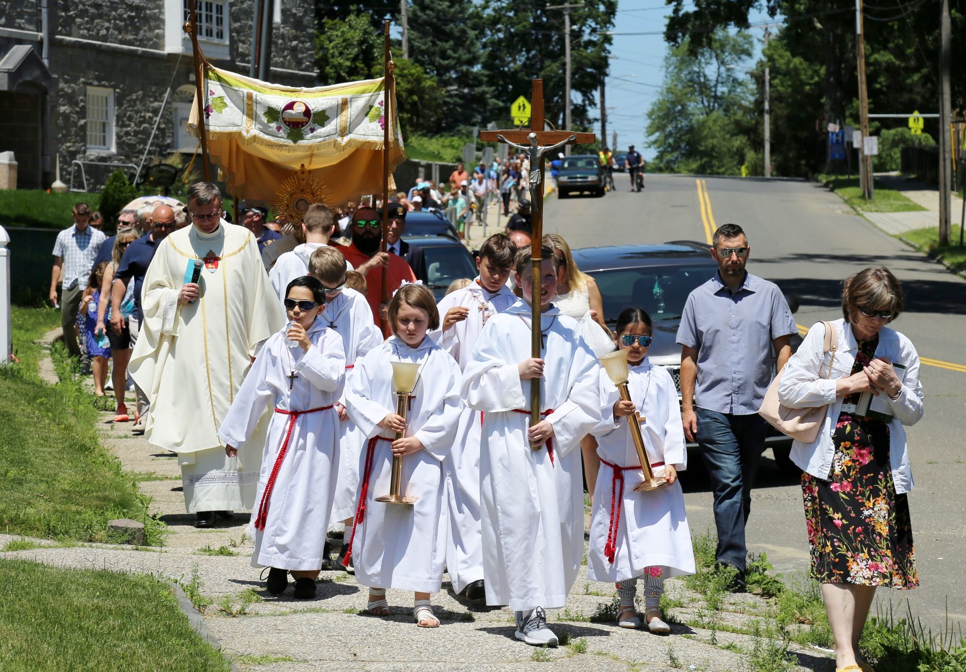 A group of people in white robes are walking down a street.