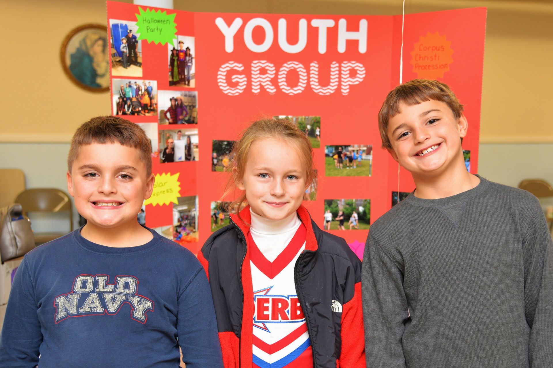 Three children stand in front of a sign that says youth group