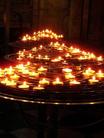 A bunch of lit candles on a table in a dark room