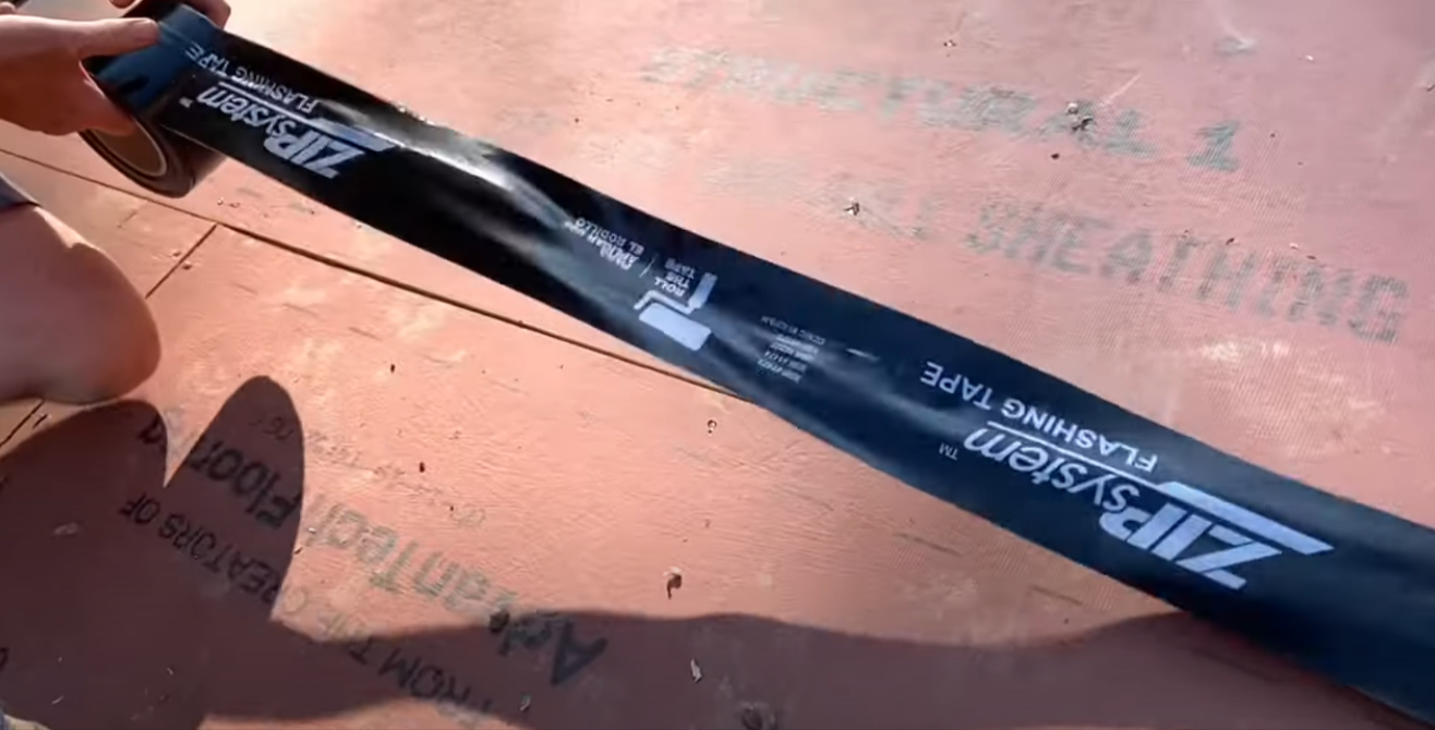 Applying sheathing tape during garage construction