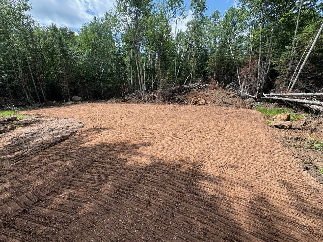 Brown soil patch cleared for construction, surrounded by trees.