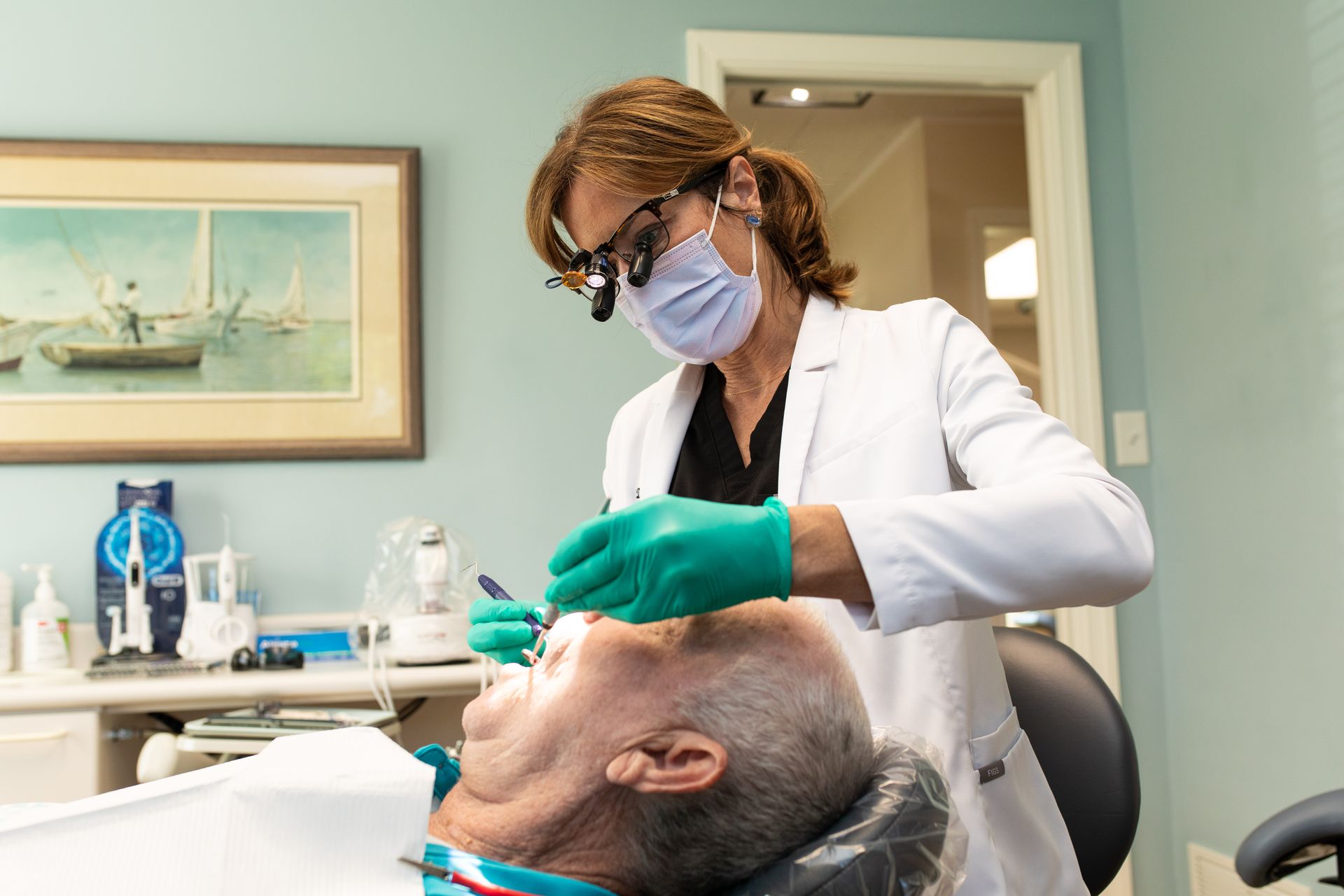 Woman in white holds up dental X-ray while speaking with a patient in a bright clinic