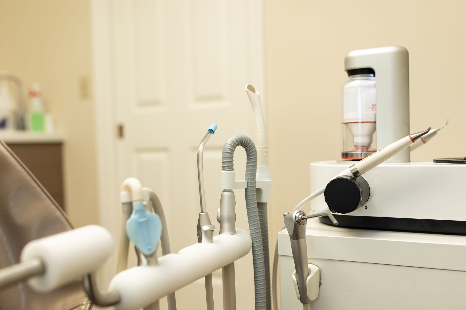 Dental exam room with chair, tools, and equipment beside a counter