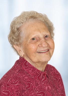 Smiling elderly woman in a red patterned blouse against a light background