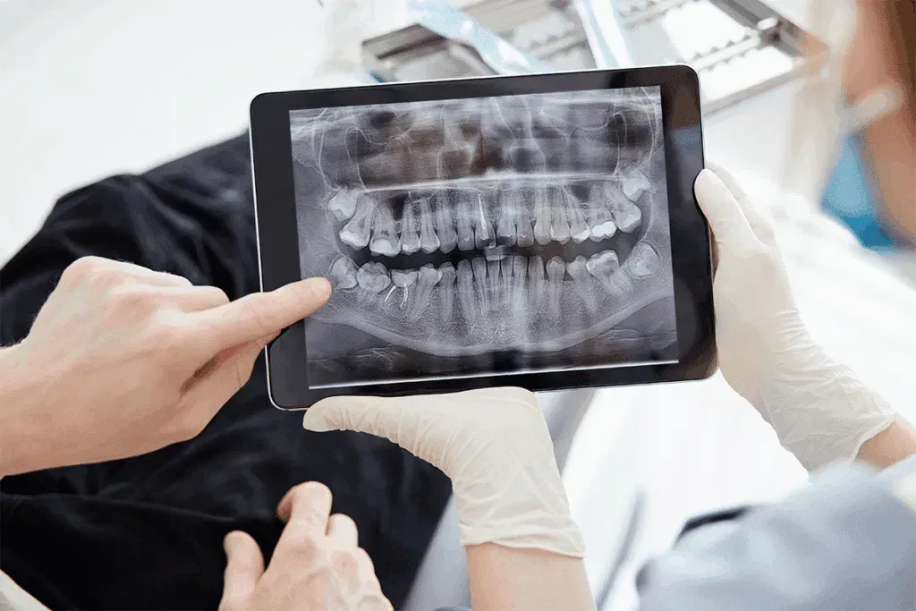 Dentist showing a dental X-ray on a tablet to a patient in a clinic