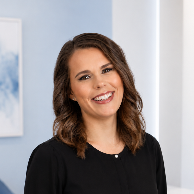 Smiling woman in a black top standing indoors against a light blue background