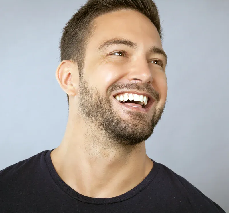 Smiling man with short beard looking up against a light blue background