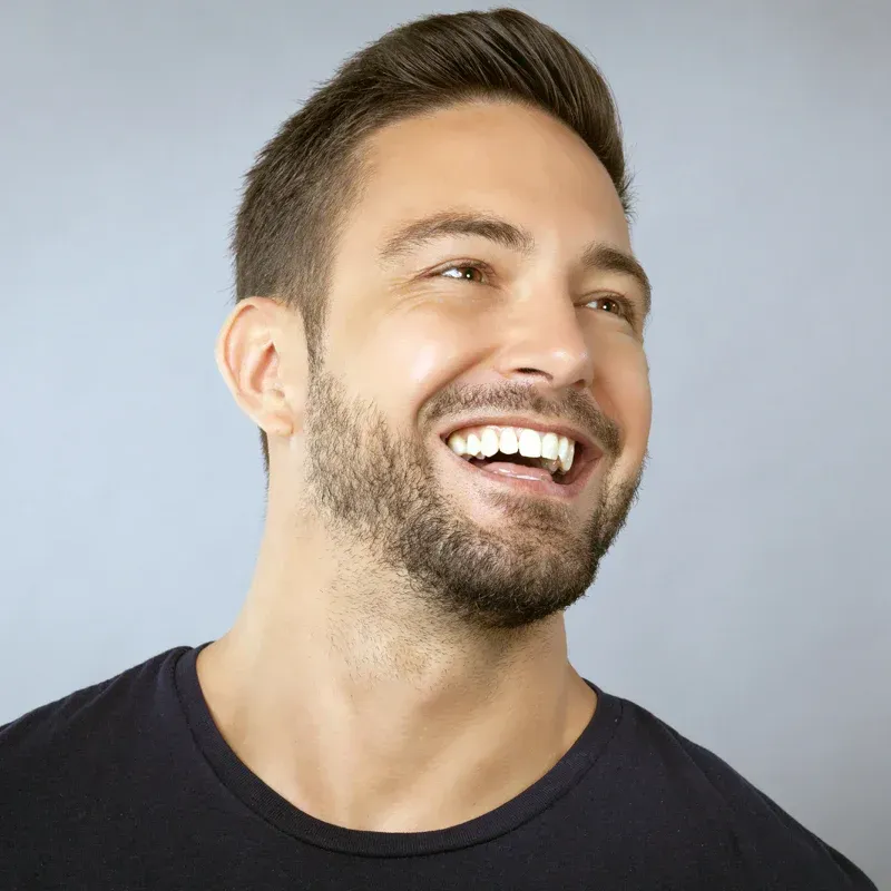 Smiling man with short beard looking up against a light blue background