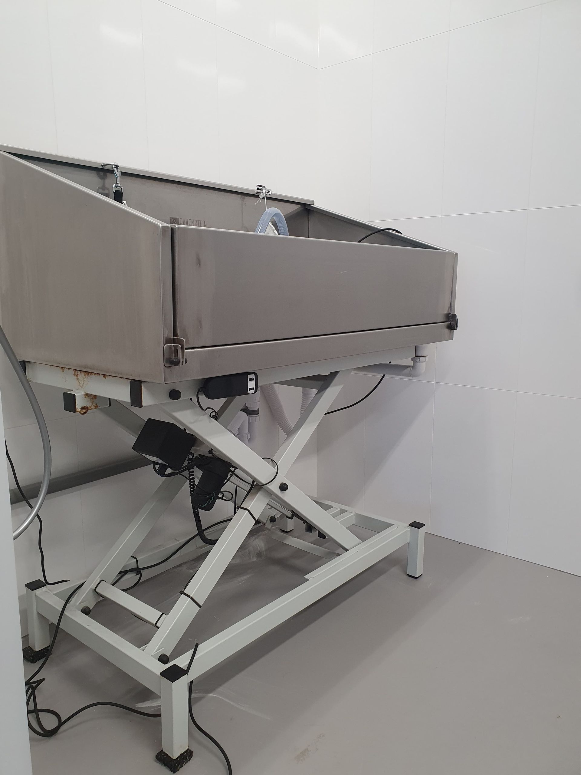 Kanteltafel van roestvrij staal met schaarlift in een witte kamer.