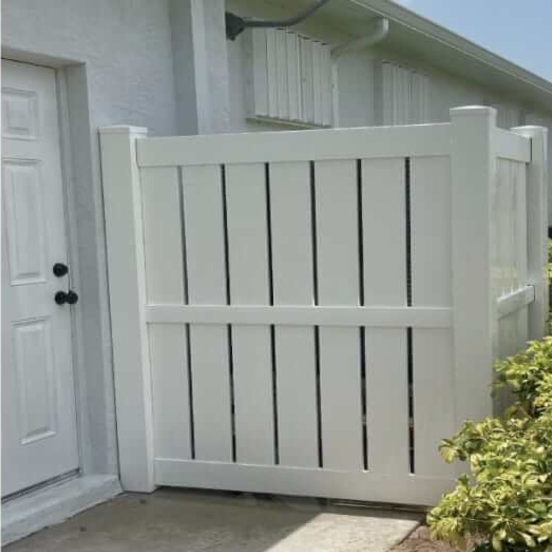 A white fence is sitting in front of a white house.