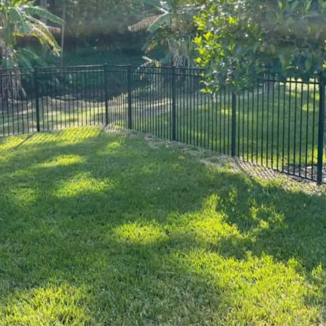 A metal fence surrounds a lush green lawn.