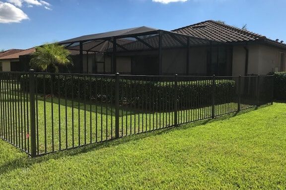 A house with a screened in porch and a metal fence surrounding it.