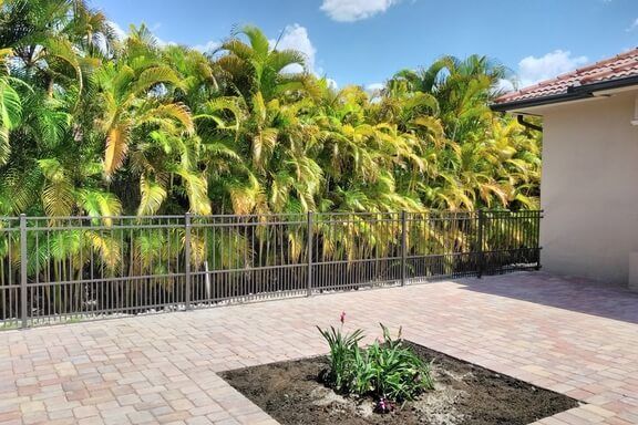 A patio with a fence and palm trees in the background