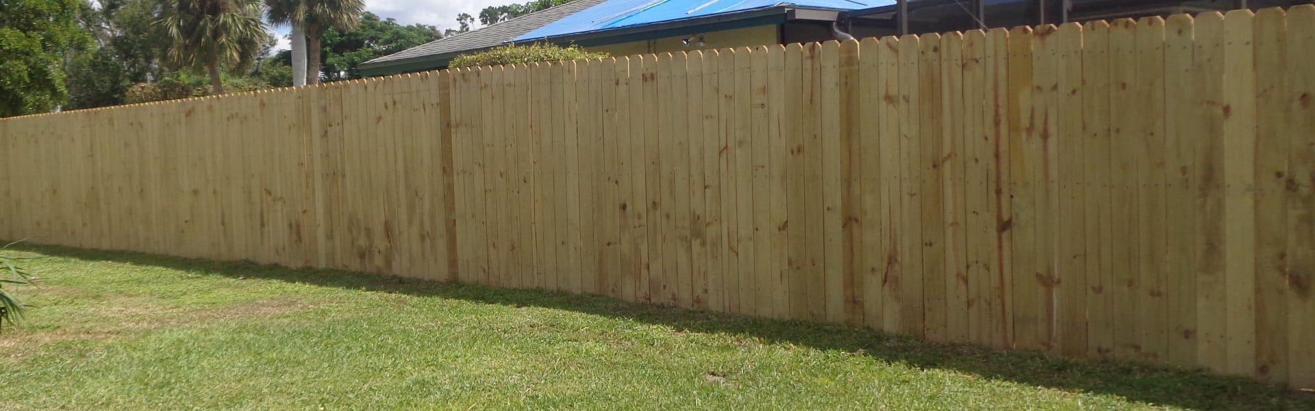 A wooden fence is sitting in the middle of a lush green yard.