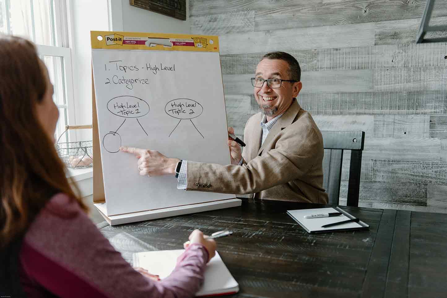 A man is giving a presentation to a woman while sitting at a table.