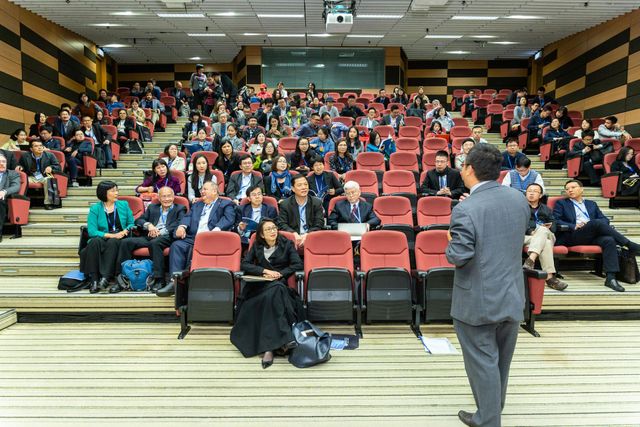 A man is giving a presentation to a large group of people in an auditorium.