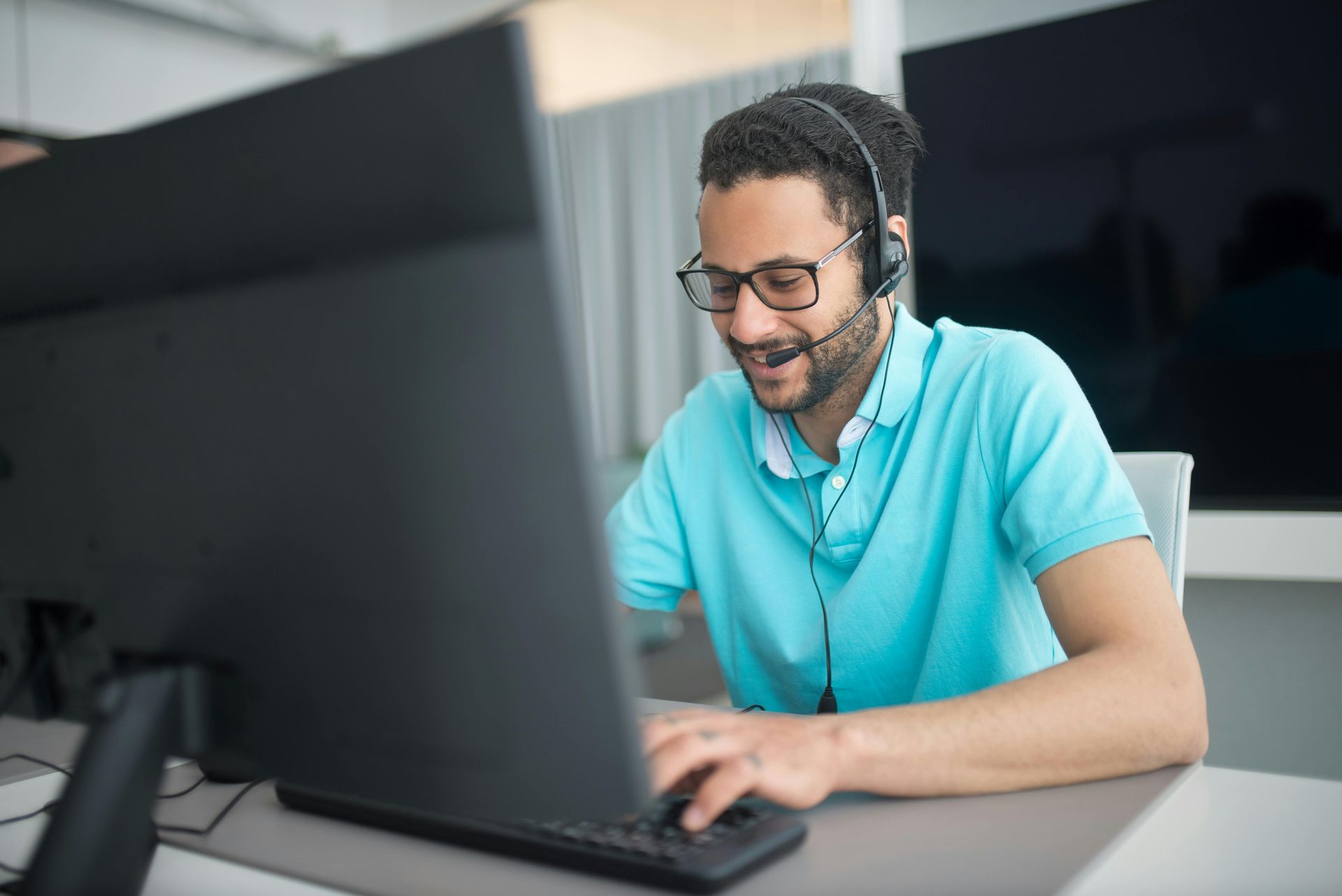 A man wearing a headset is sitting in front of a computer.