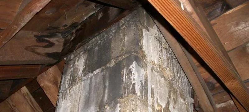 a chimney is sitting under a wooden ceiling in an attic .