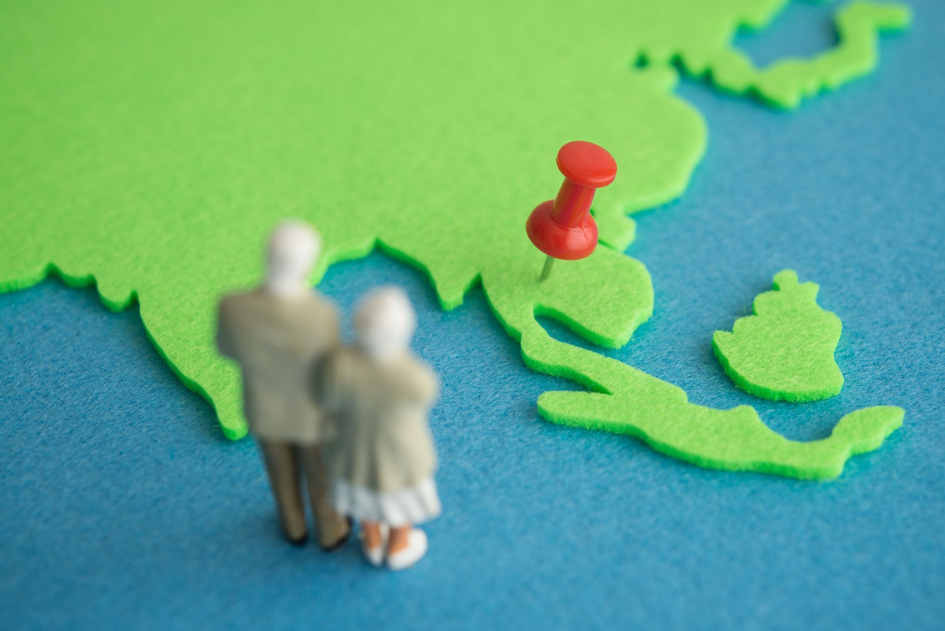 Miniature figures on a map with a red pin marking a location in Southeast Asia