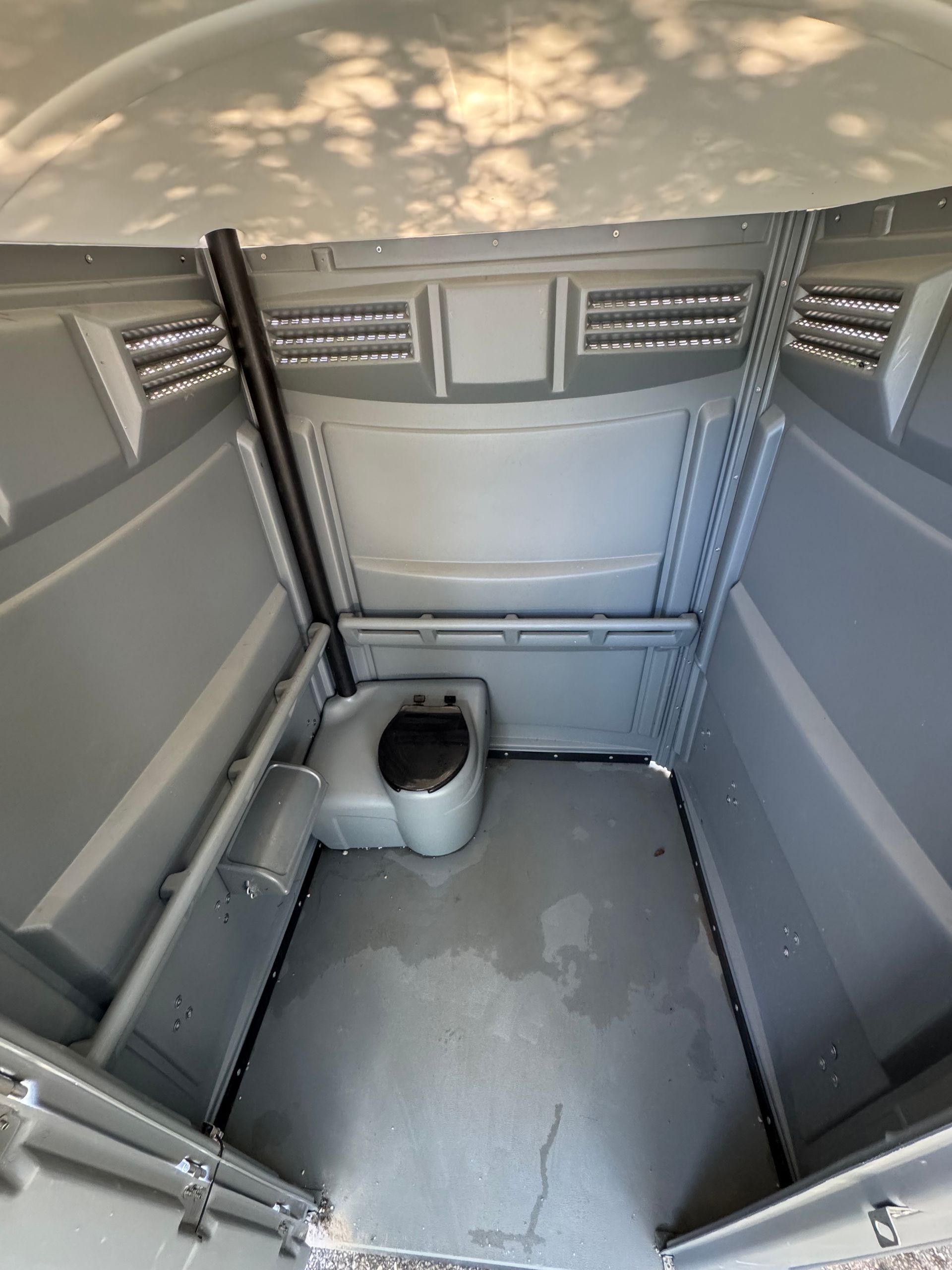 The inside of a portable toilet with a toilet in it.
